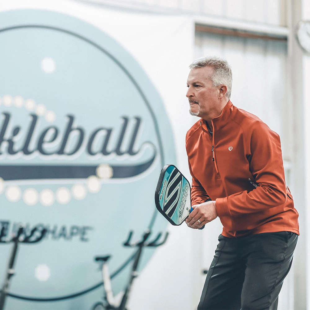 older man playing pickleball