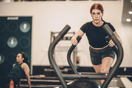 woman pushing sled across turf