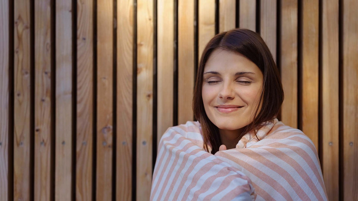 woman sitting in sauna with towel